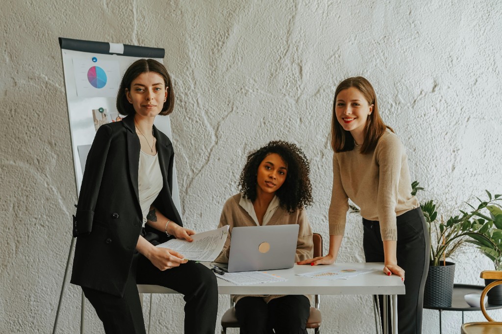 Three women collaborating at a desk in a bright office